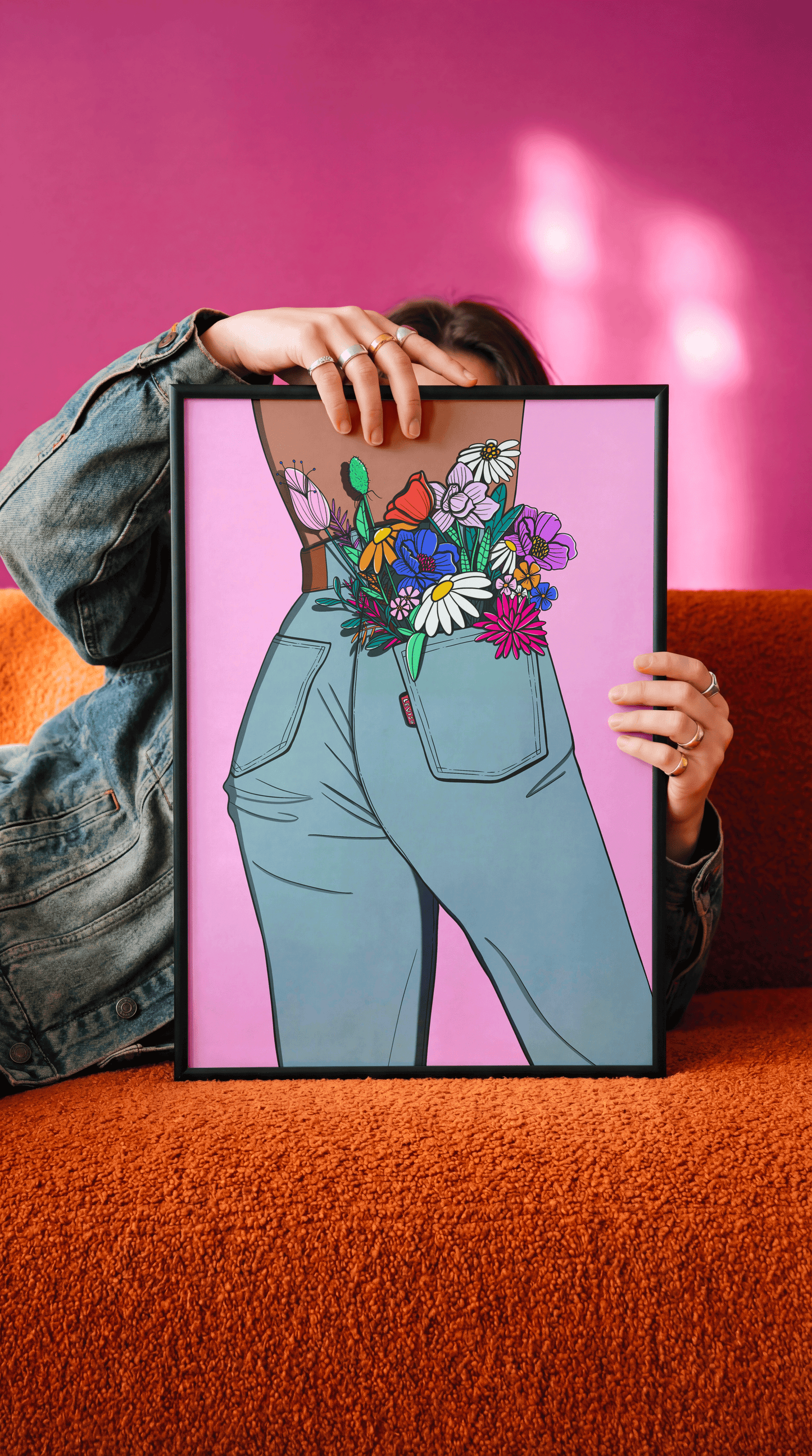 Affiche Flower in my pocket tenue dans son cadre noir, fond rose fuchsia et canapé orange